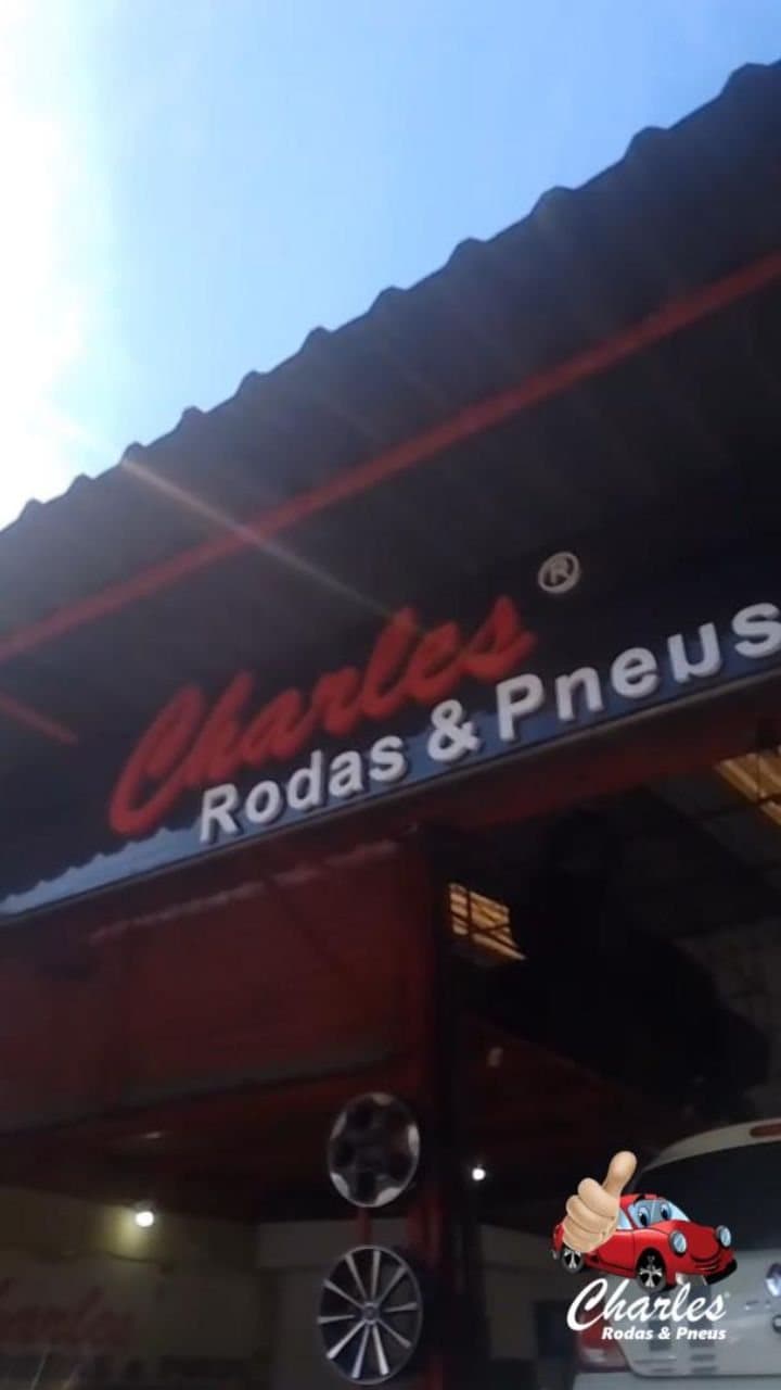 Fachada iluminada da Charles Rodas & Pneus à noite